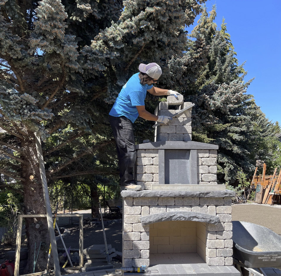 Prefessional mason building stone fireplace in backyard